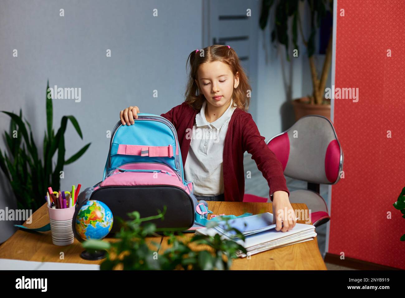 Girl packing school books in bag Stock Photos and Images