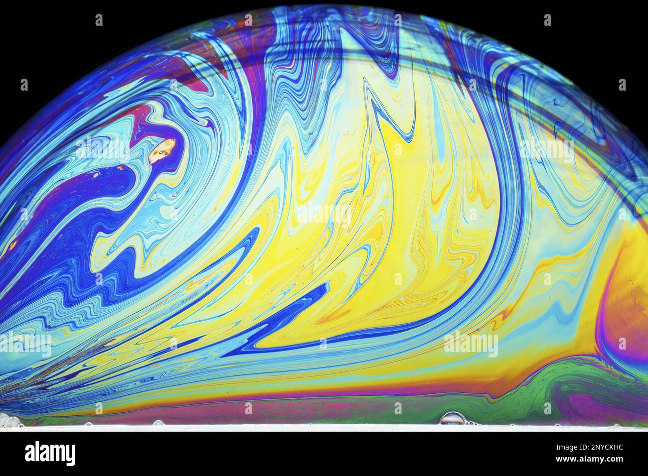 splashes of colorin a soap bubble lit from below against a dark background Stock Photo