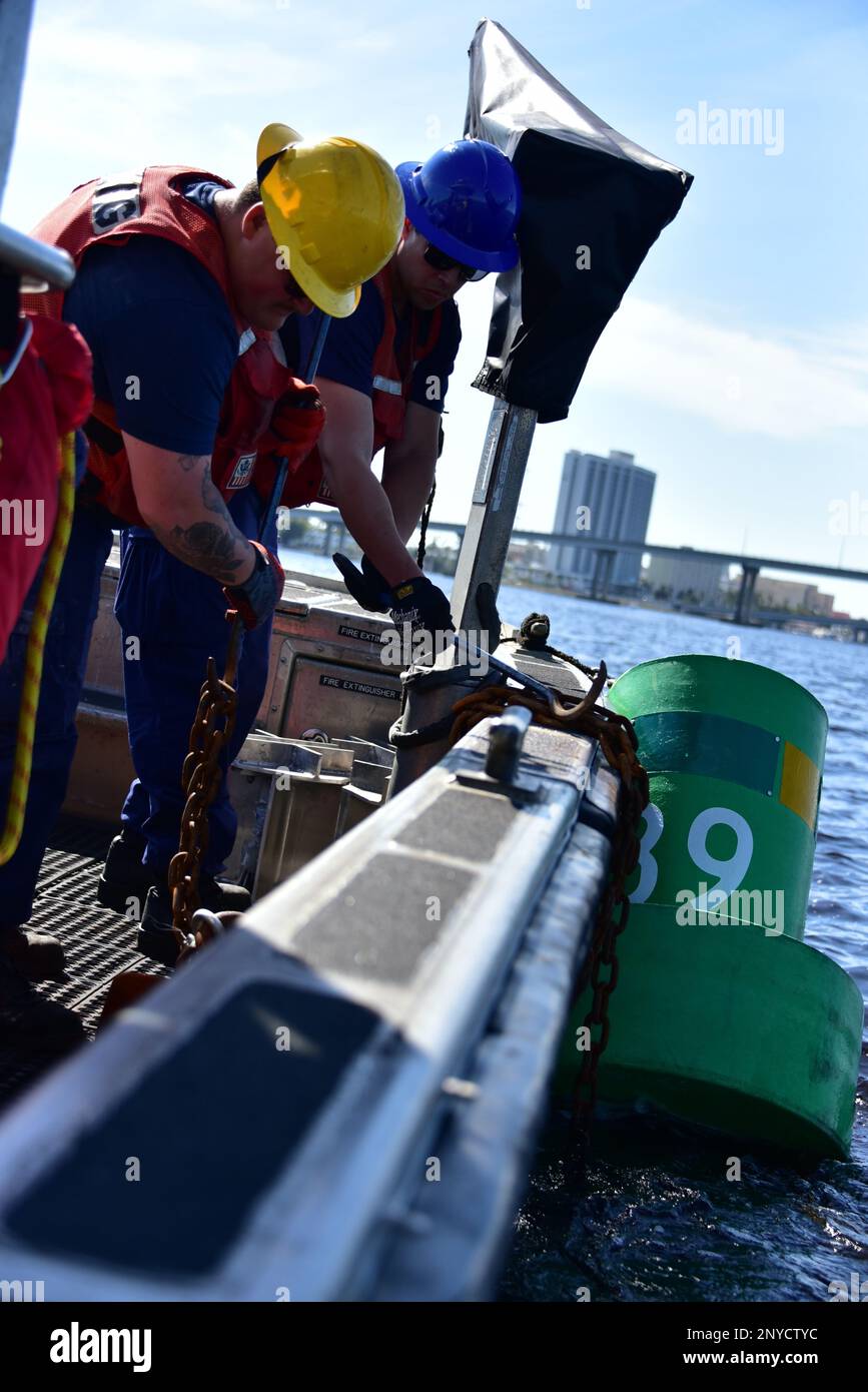 Seaman Brandon Pupo (left) and Petty Officer 3rd Jonathon Santiago Olmo drop a buoy in Fort Myers, Florida, Jan. 19, 2023. The buoy act as a channel marker to help guide local boaters out in the water to keep them safe. Stock Photo