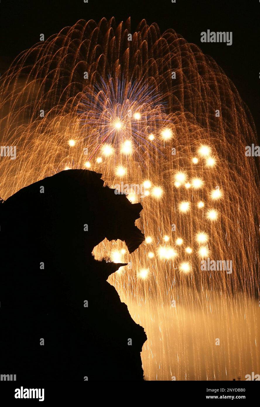 A Lion Rock, know as shishiiwa, is silhouetted agaisnt fireworks in the ...