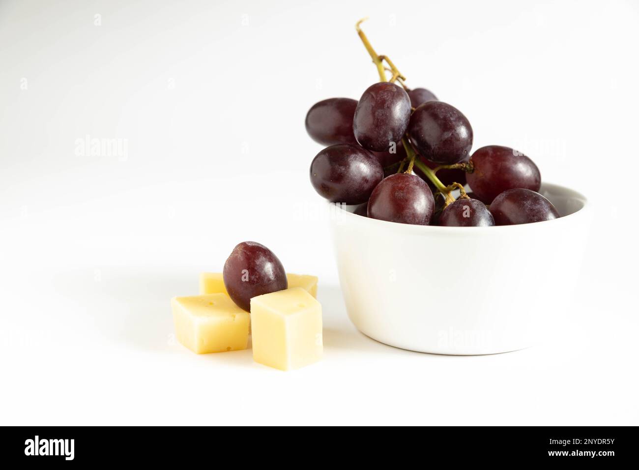 front view on red grapes with cheese isolated on a white background