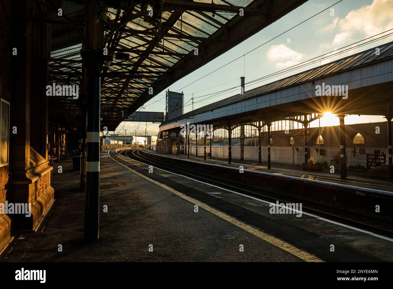 Empty platforms and railway tracks on the West Coast main Line at sunset Penrith North Lakes station, Penrith Cumbria Stock Photo