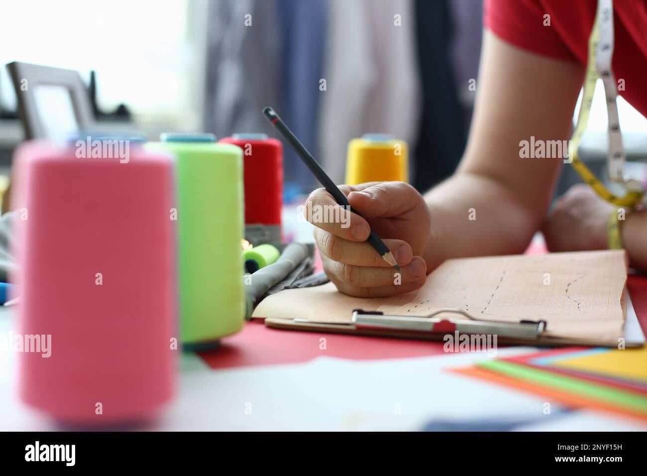 Female fashion designer stylist working with sketches in studio closeup ...