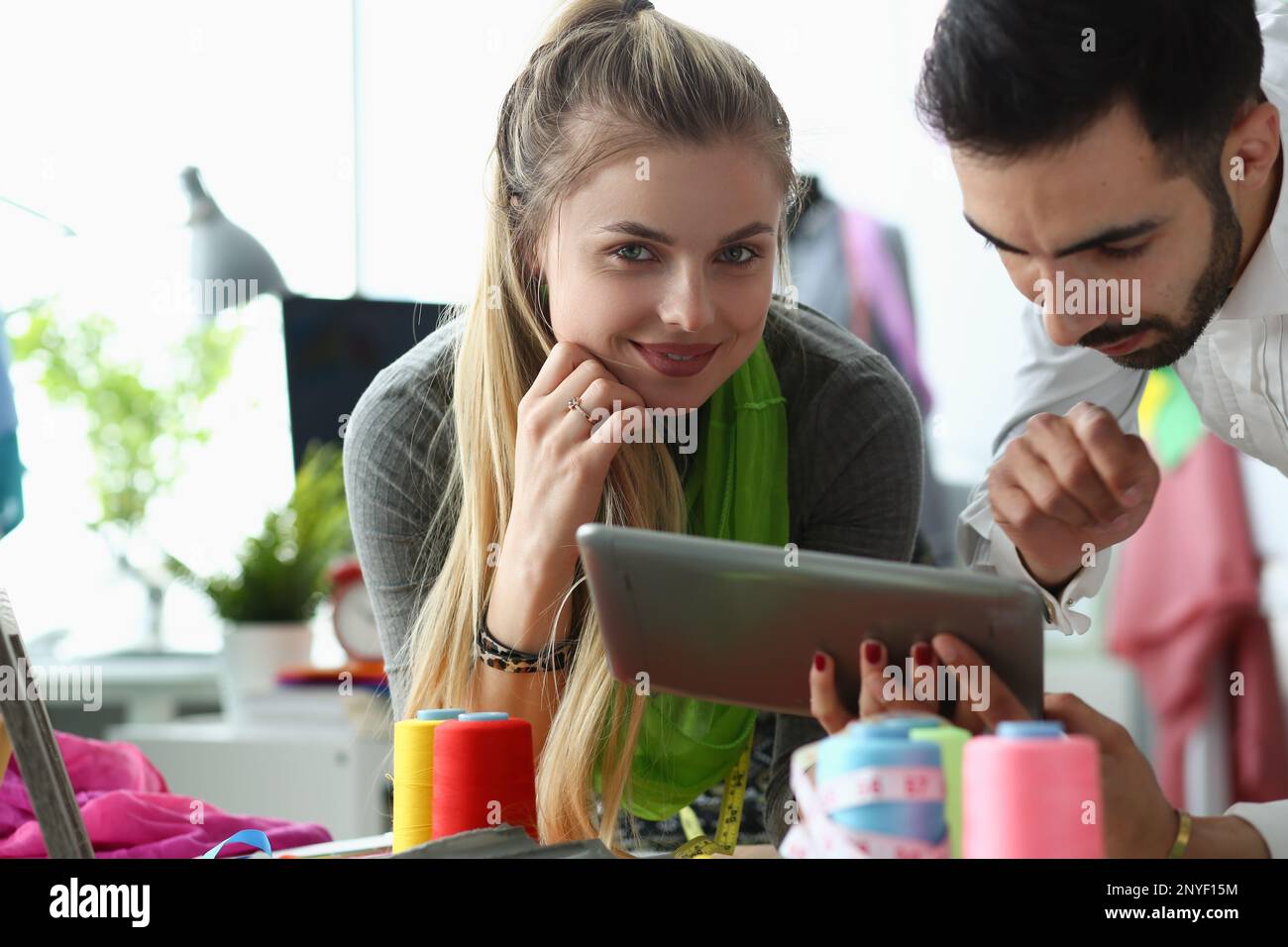 Professional tailors work on project using tablet in fashion design studio Stock Photo
