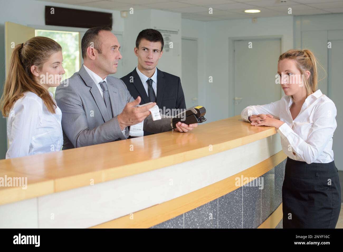 men behind reception desk looking at computer Stock Photo - Alamy
