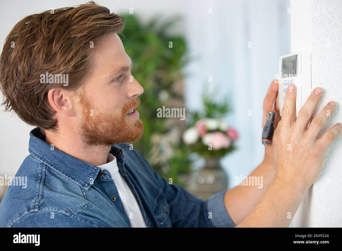 young male electrician installing security system Stock Photo