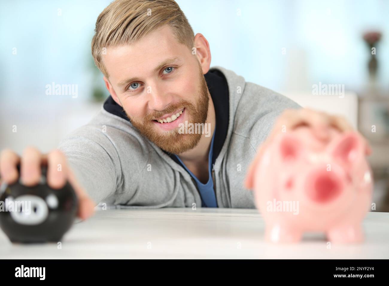 man holding two different sized piggy banks Stock Photo - Alamy