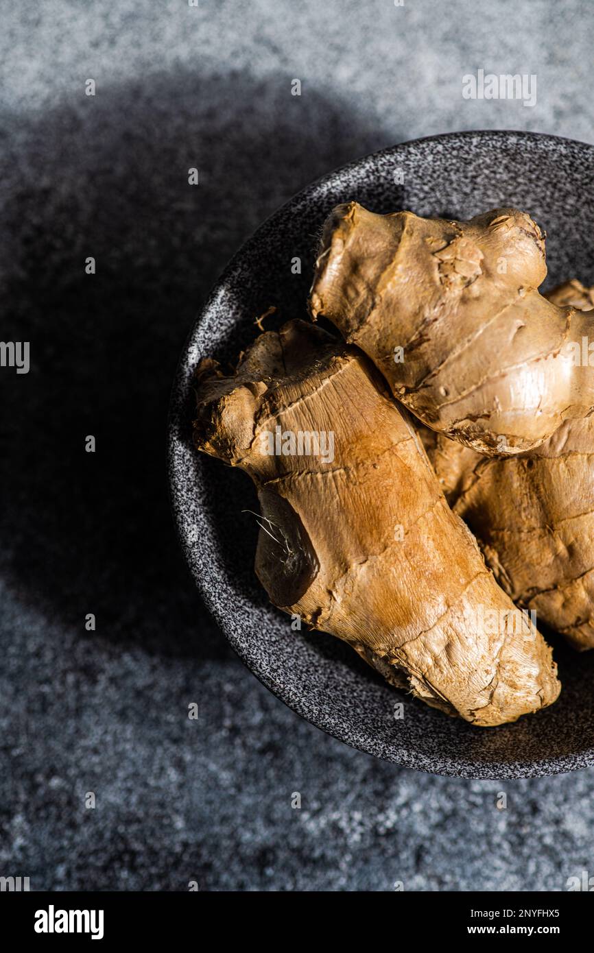 Black stone bowl with ginger roots on concrete kitchen table Stock Photo