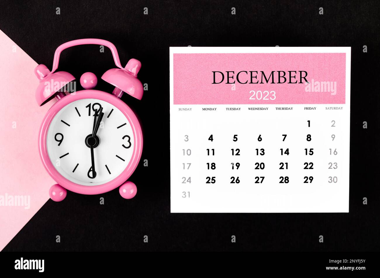 December 2023 Monthly calendar year with alarm clock on pink and black  background Stock Photo - Alamy