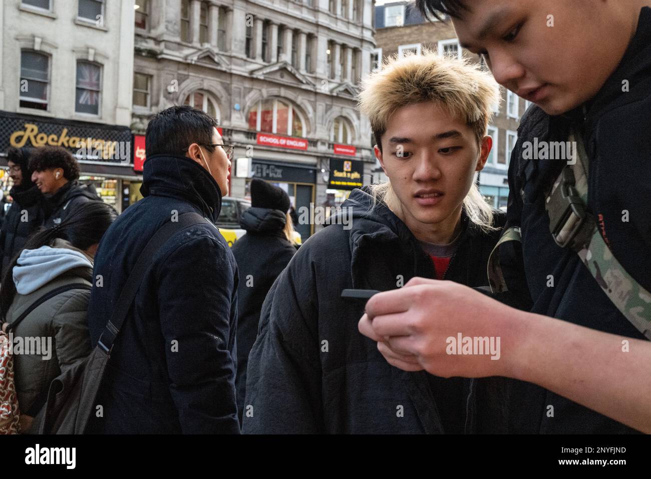 Two Asian males use a mobile/cell phone for information in city setting. London UK Stock Photo