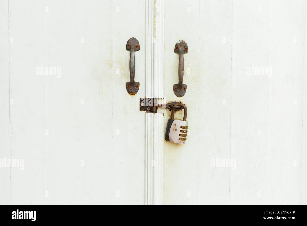 Closed padlock hangs on the white doors. Stock Photo