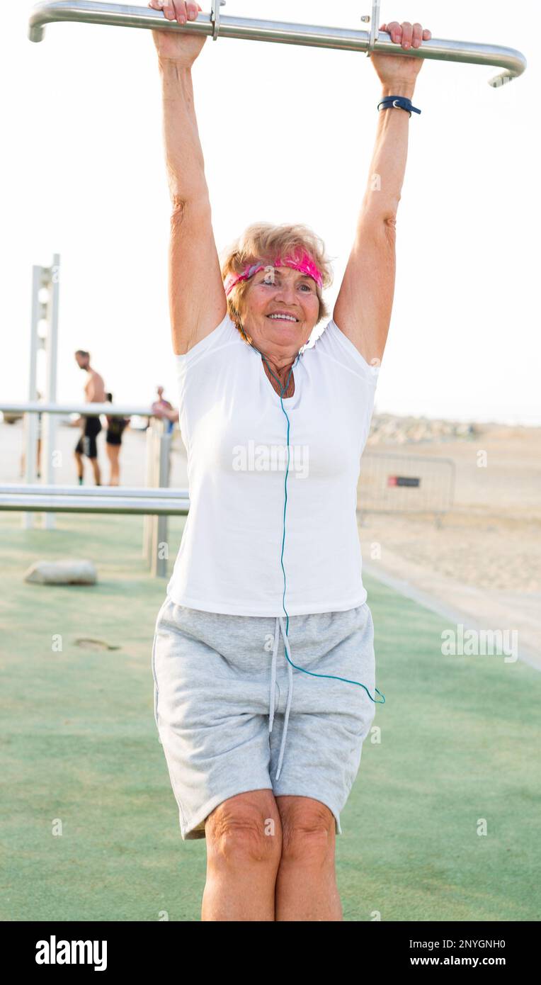 Old woman hanging from pullup bar Stock Photo Alamy