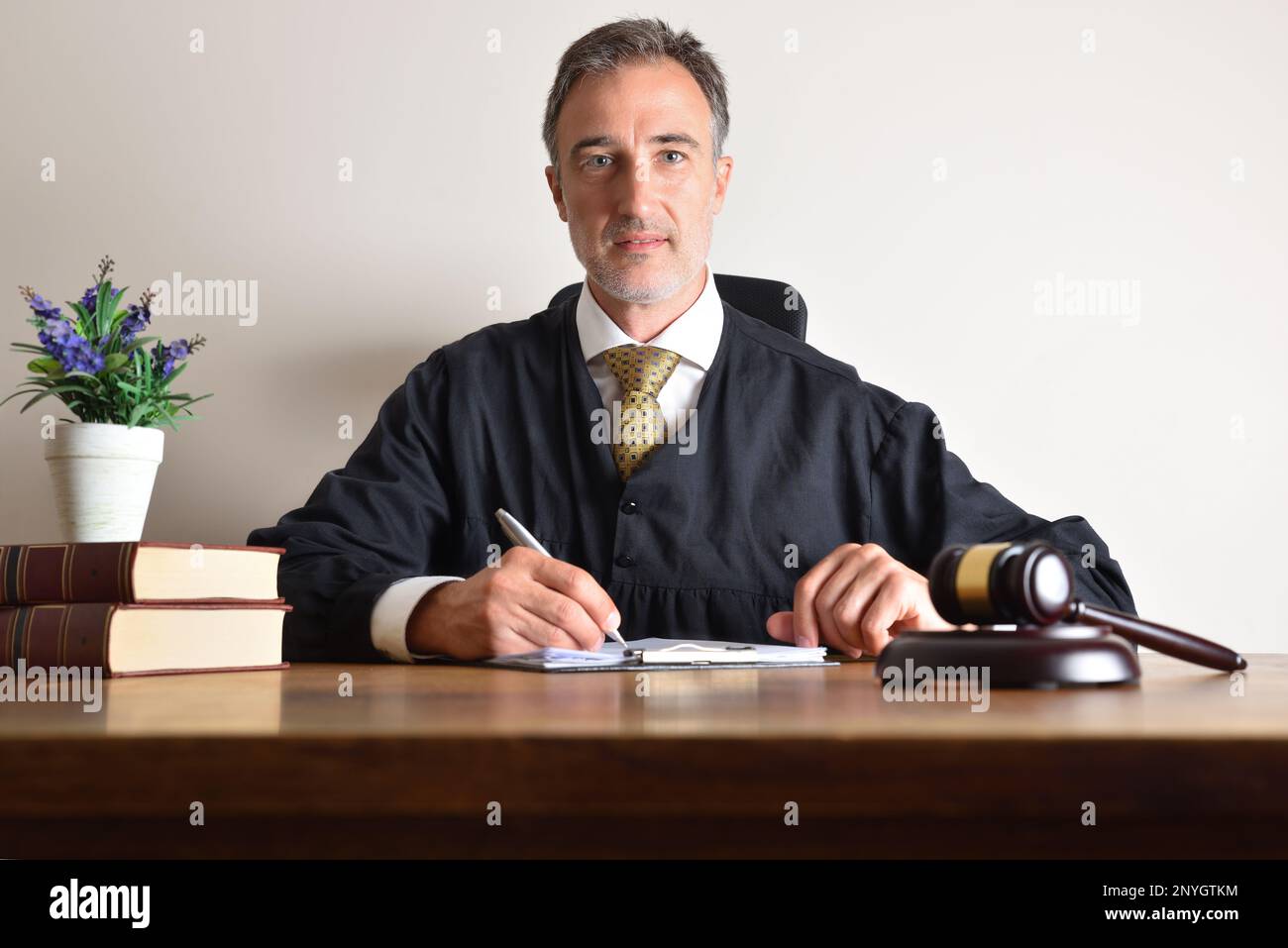 Judge working in his office looking straight ahead reviewing documents on a wooden table. Front view Stock Photo