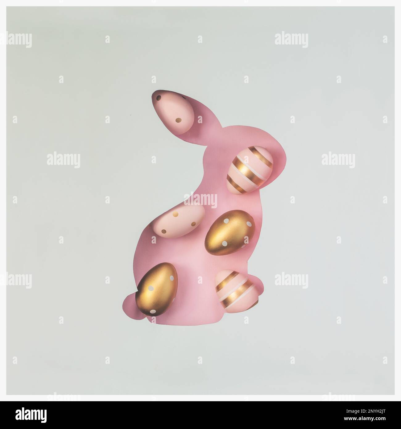 Easter bunny shape cut out with decorated Easter eggs on pink background; Top view, flat lay; Creative minimal spring or Easter background Stock Photo
