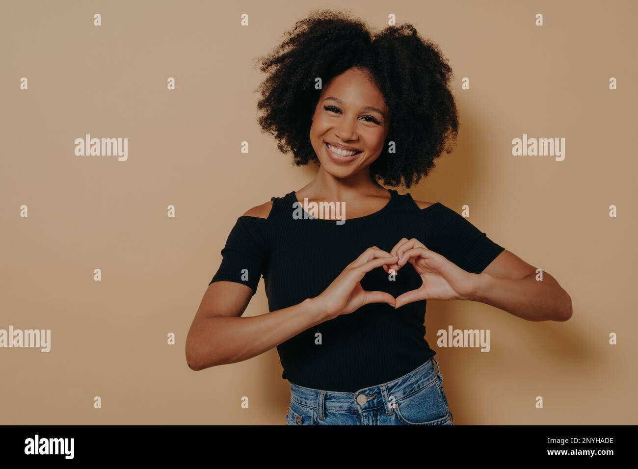 African american woman wearing casual clothes showing love gesture with heart shaped fingers, expressing healthy and marriage symbol with hands. Posit Stock Photo