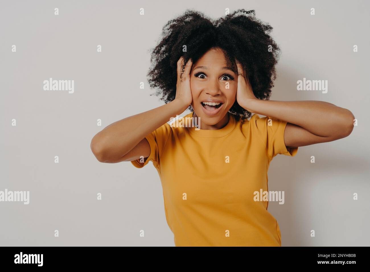 Woman plugging ears with arms does not want to listen hard rock or loud music. African American young female ignoring noise covering head with hands a Stock Photo