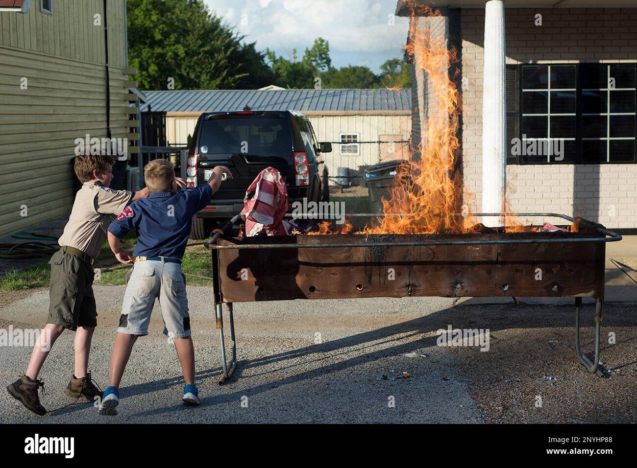 Landon Wilson, 11, and Lance Krieg, 8, throw a flag into the fire