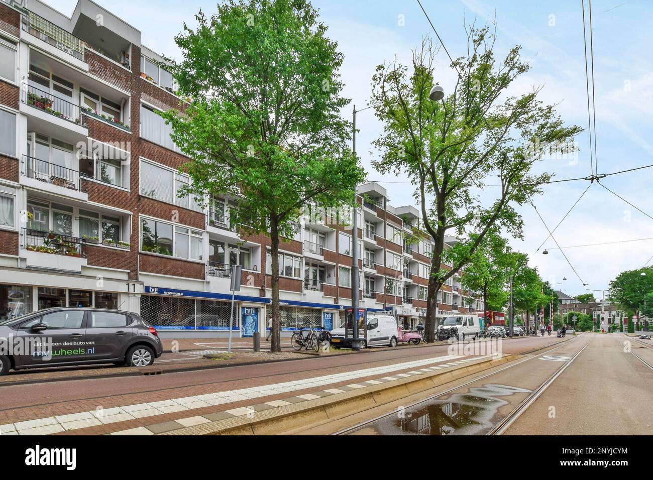 a city street with cars parked on the side and trees in the middle part ...