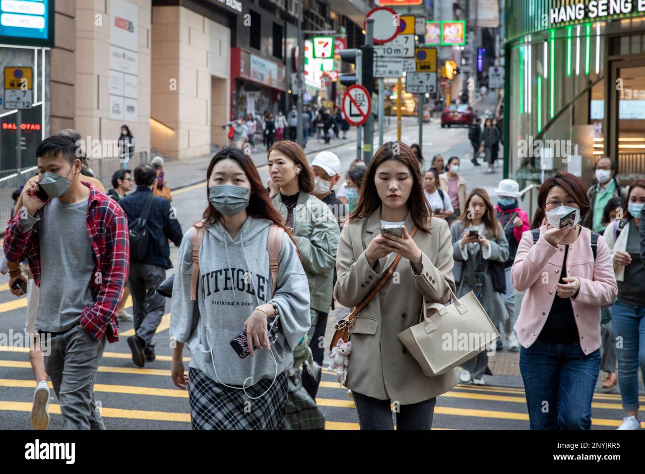 Pedestrians wearing masks and others without masks are seen crossing