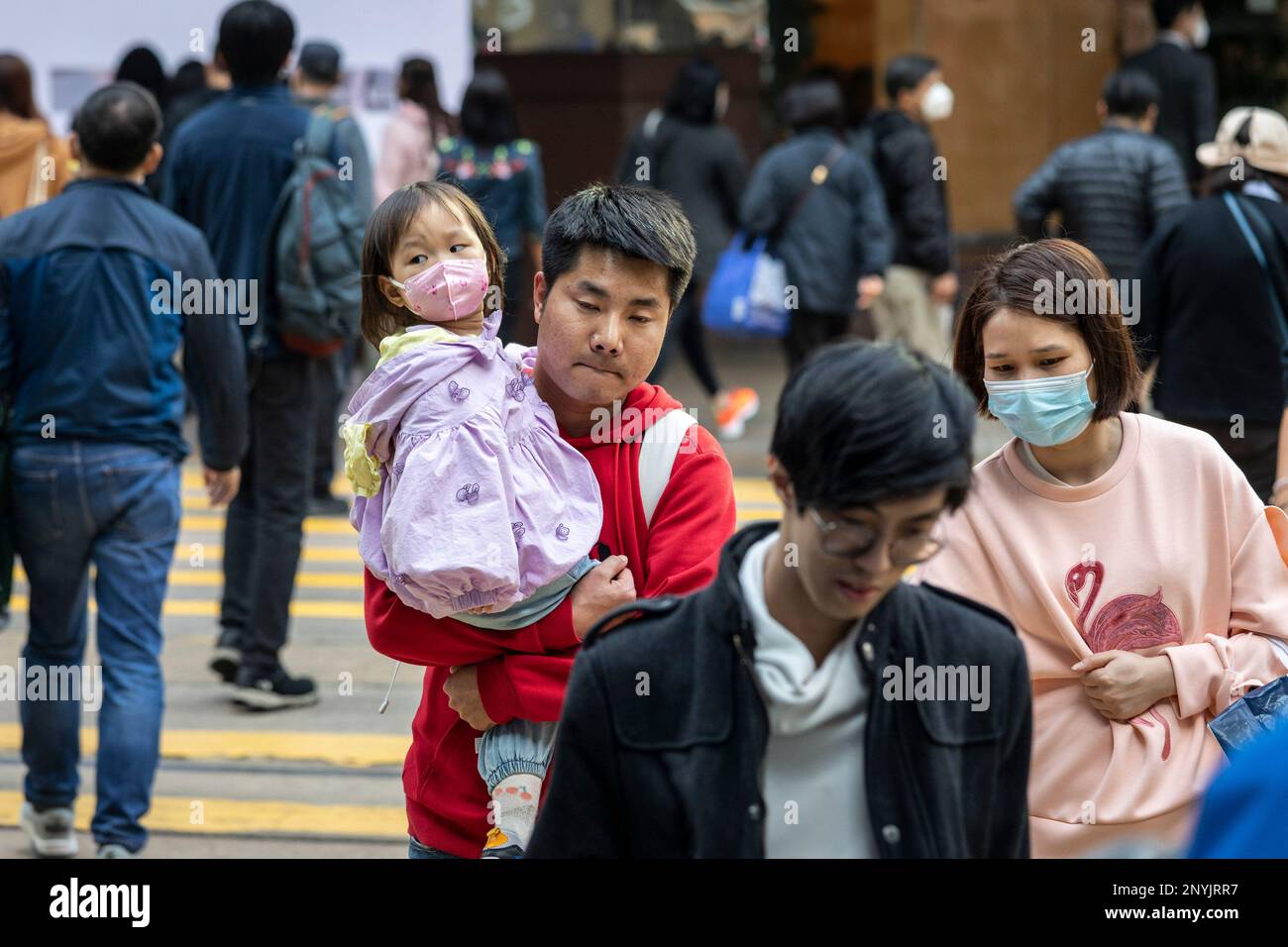 A maskless man is seen carrying her daughter wearing a mask as they
