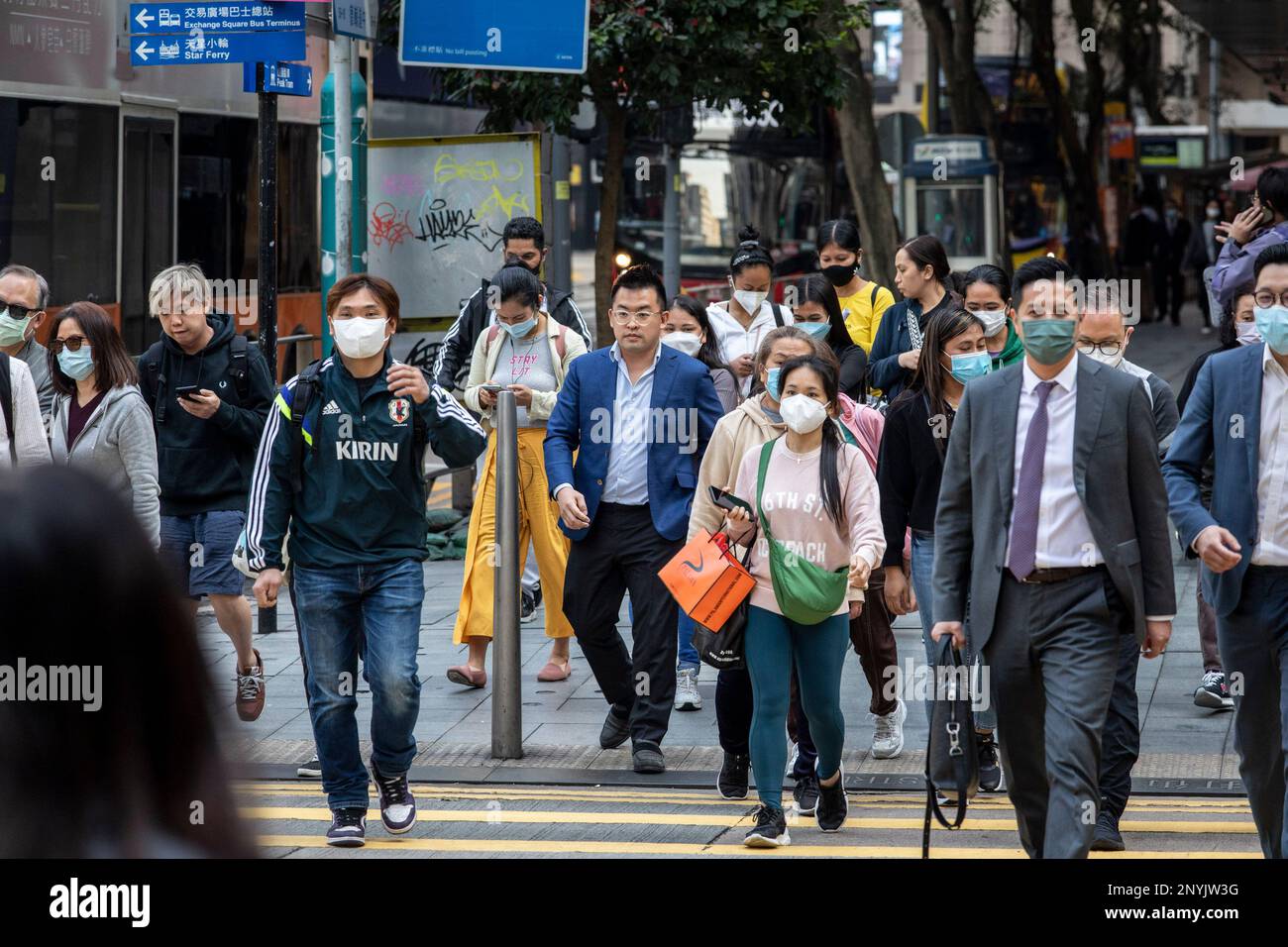 Pedestrians wearing masks and others without masks are seen crossing