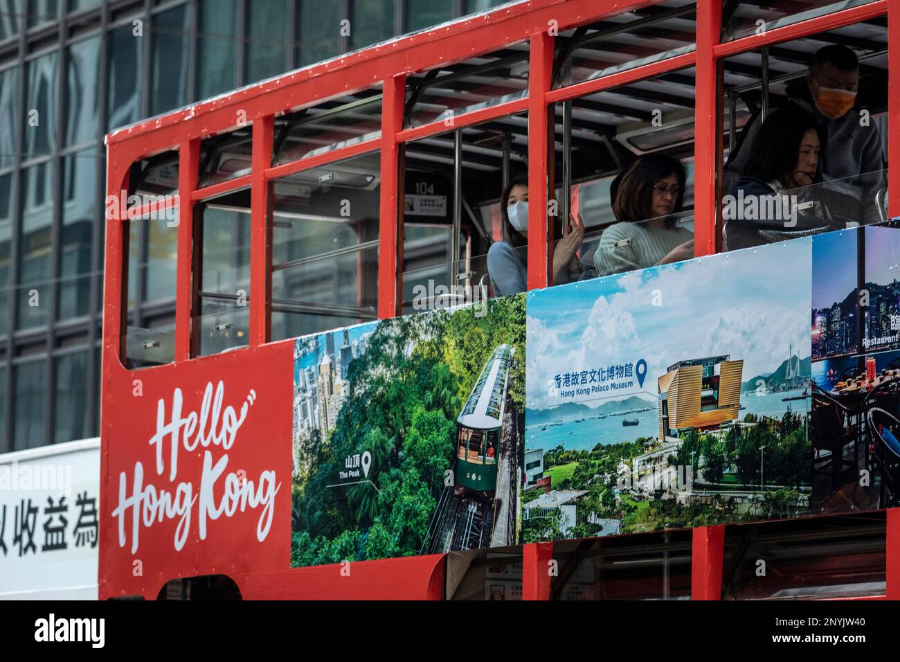 People are taking a tram with words "Hello Hong Kong" from the Hong