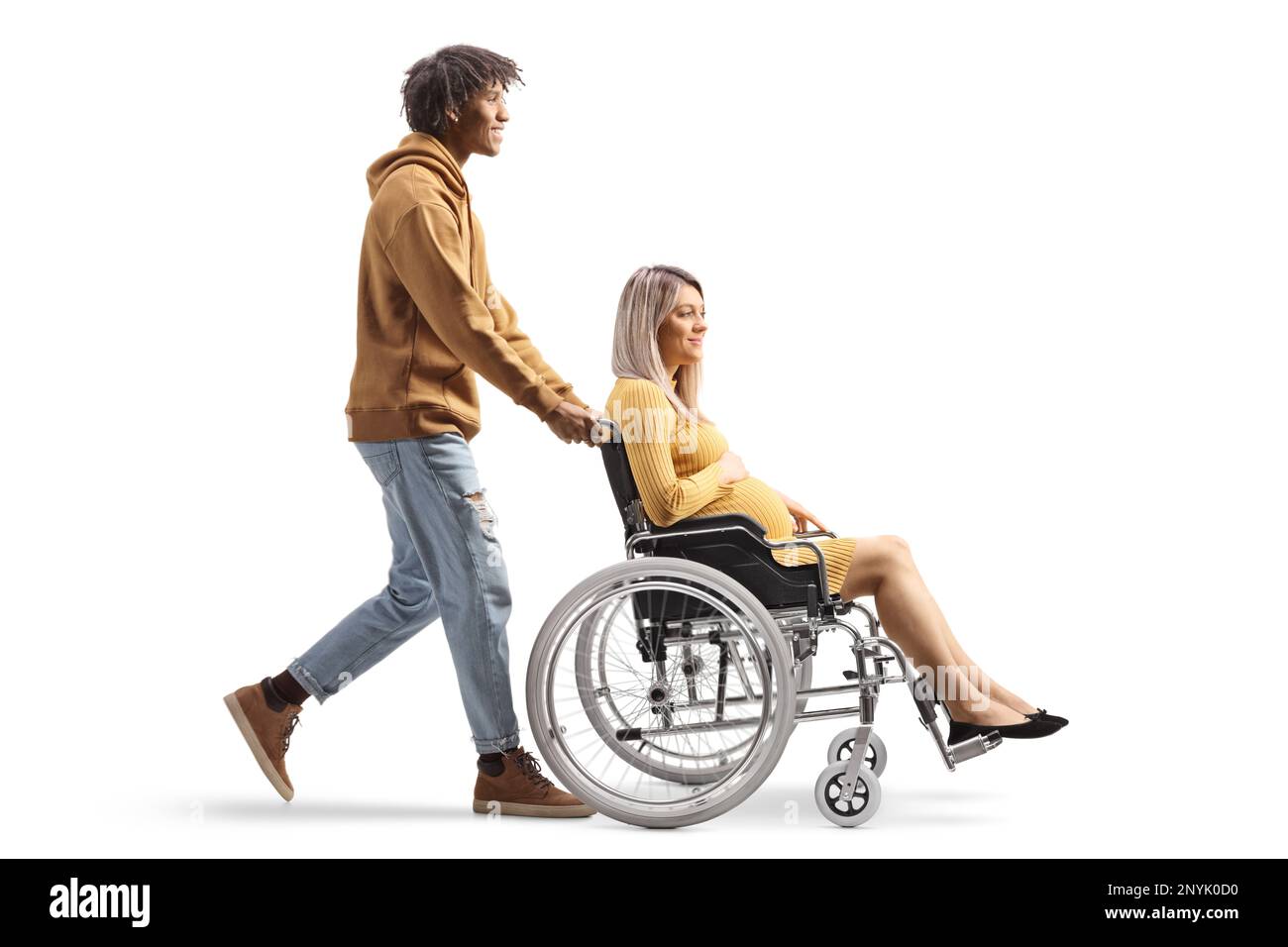 Full length profile shot of an african american man pushing a caucasian pregnant woman in a wheelchair isolated on white background Stock Photo