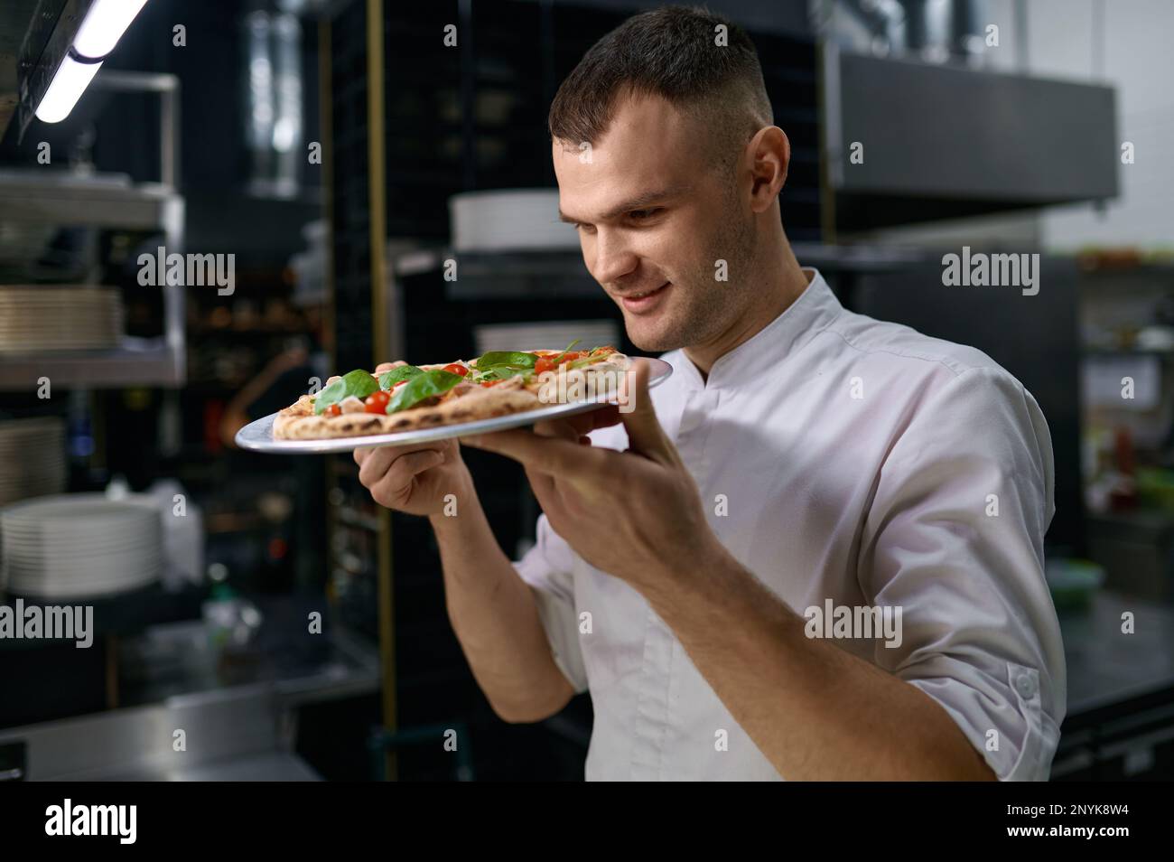 Satisfied male chef enjoying smell of just baked pizza Stock Photo