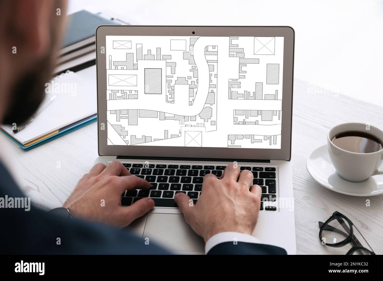 Man analyzing cadastral map on laptop at table, closeup Stock Photo