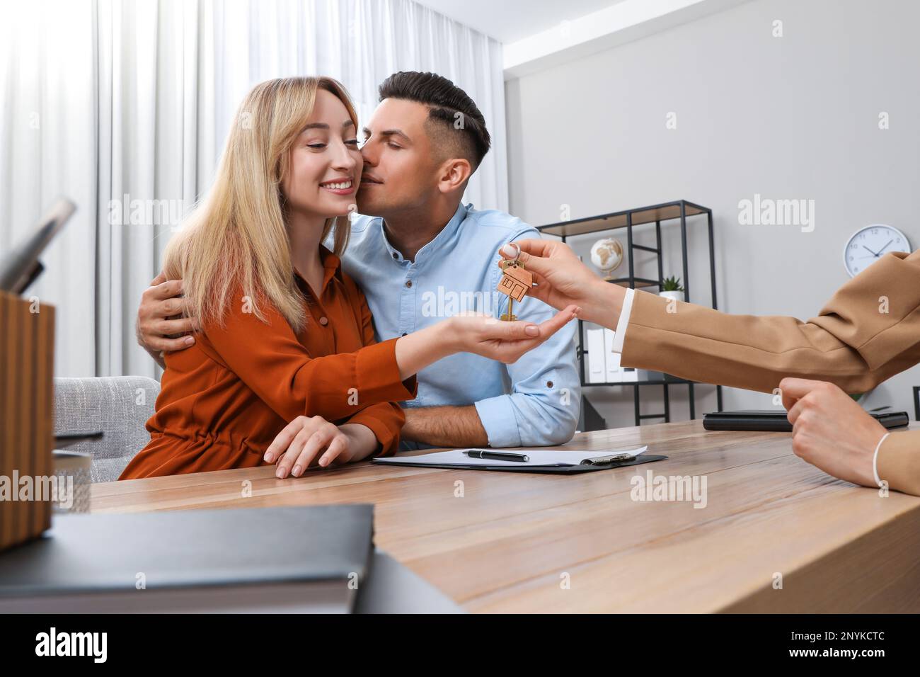 Real estate agent giving house key to couple at table in office Stock ...