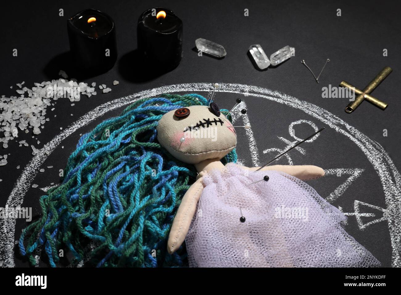 Female voodoo doll with pins surrounded by ceremonial items on black ...