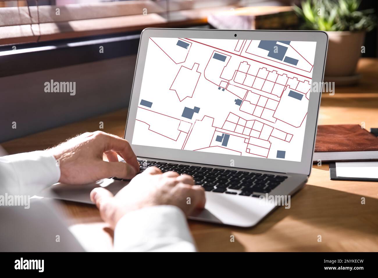 Man analyzing cadastral map on laptop at table, closeup Stock Photo
