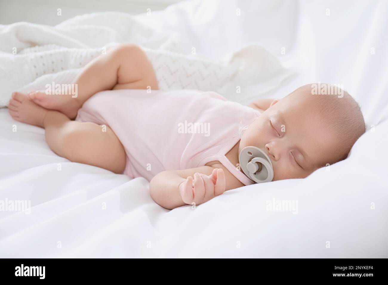 Cute little baby with pacifier sleeping on bed Stock Photo - Alamy