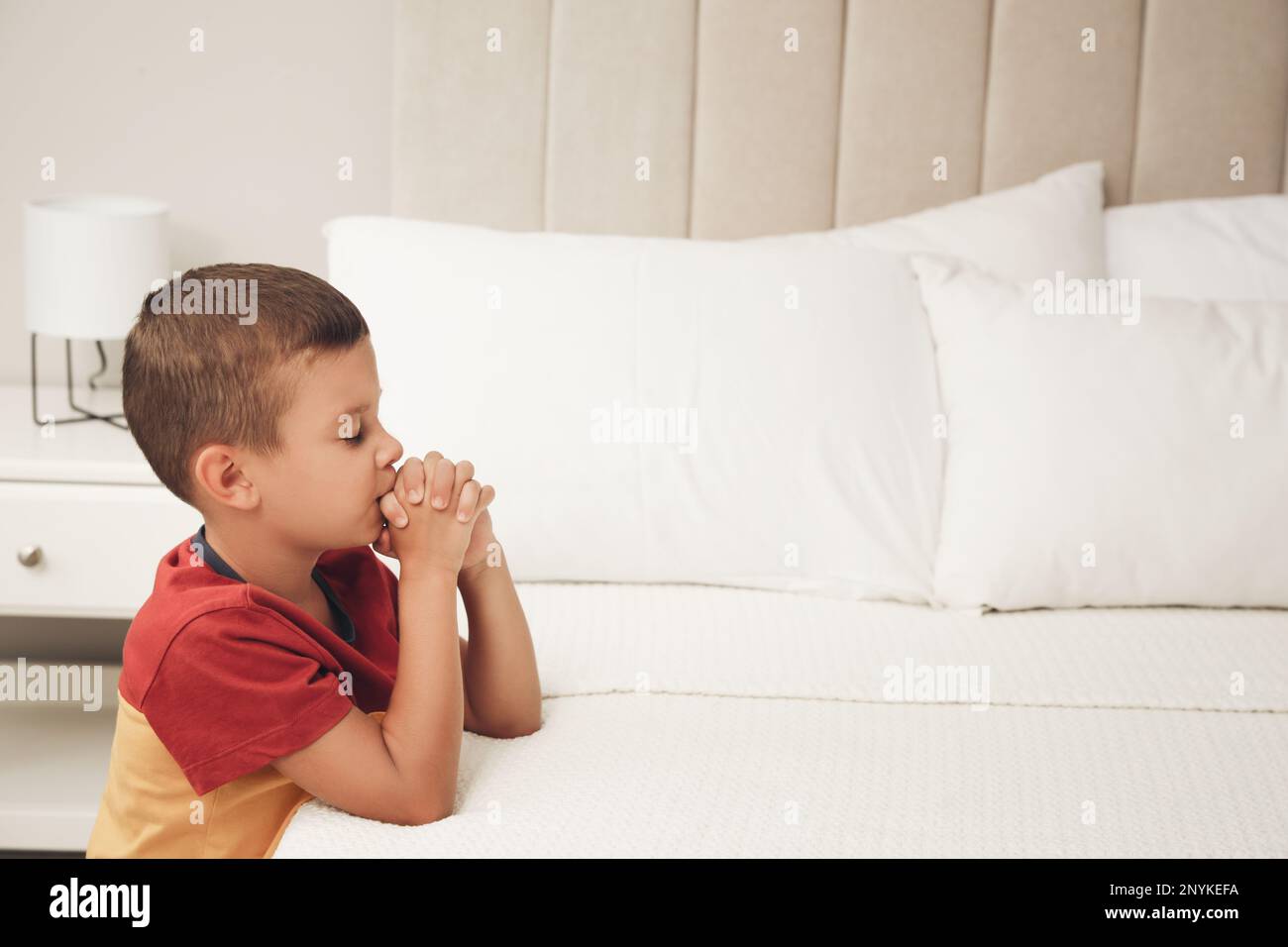 Cute little boy with hands clasped together saying bedtime prayer at ...