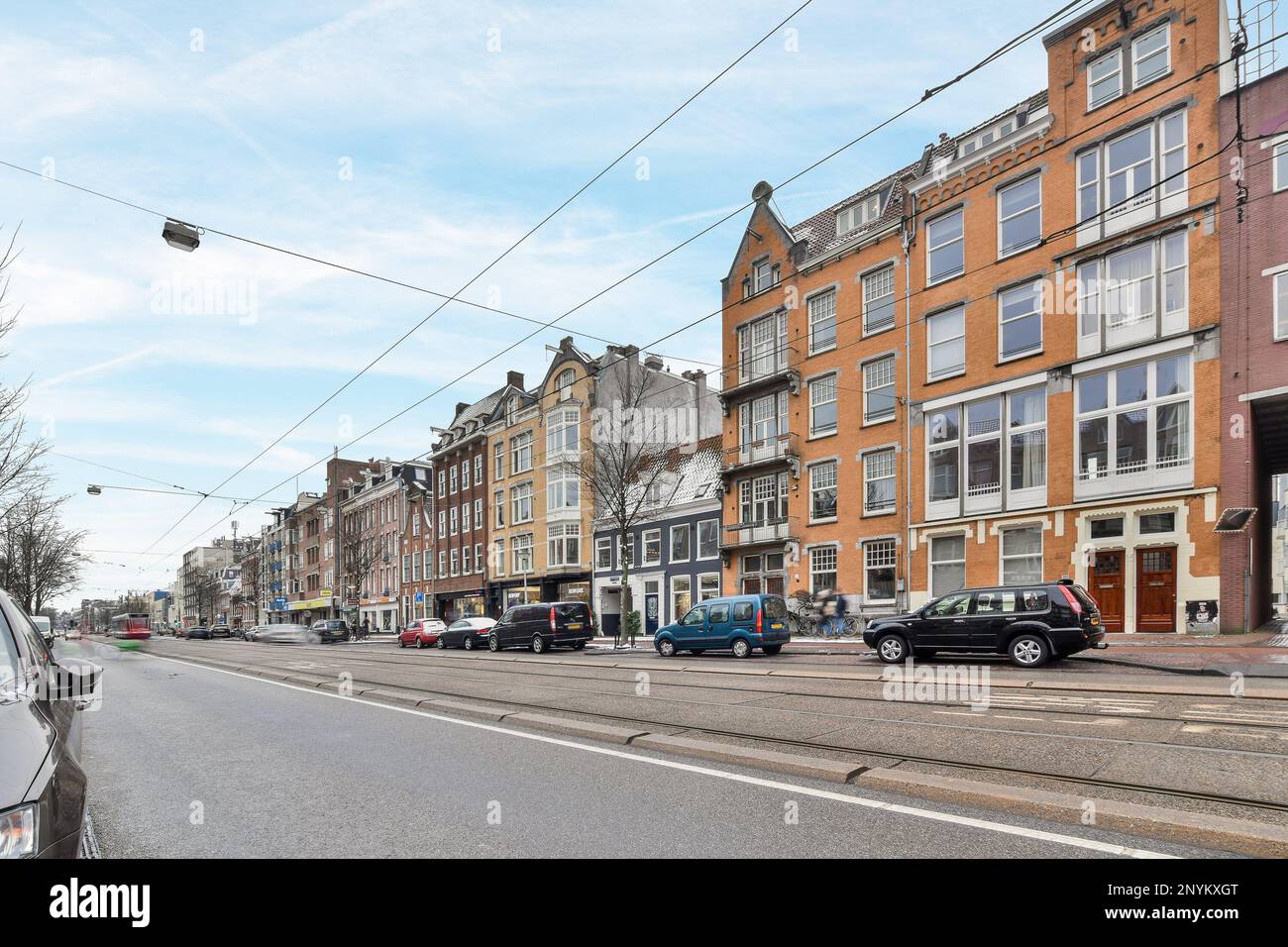 a city street with cars parked on the side and buildings in the back ...
