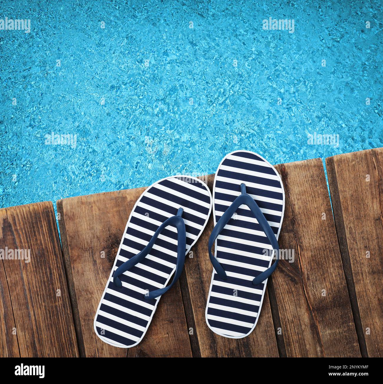 Pair of flip flops on wooden deck near swimming pool, top view Stock ...