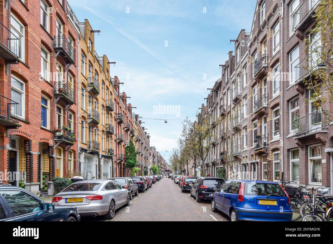 a city street with cars parked on the side and people walking down the ...