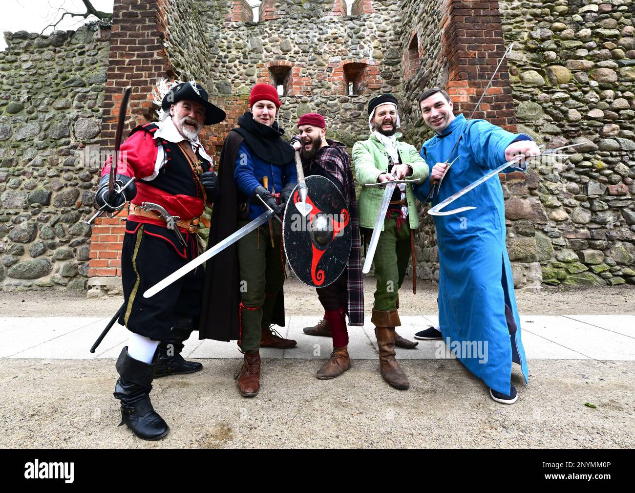 02 March 2023, Brandenburg, Bernau: Members of the Bernauer Briganten around Brigantenchef Bernd Eccarius-Otto (l) stand in front of the city wall during a press event for the upcoming 25th International Swordsmen's Meeting. In the Erich-Wünsch-Halle, about 130 swordsmen from 18 clubs and groups want to show their skills at the swordsmen's meeting on March 12, 2023. In authentic costumes and with short show interludes then among other things gladiator fights of the old Rome, the shield wall of the Wikinger, the Kendo of the Japanese Samurai, the Gatka of the Indian Sikh or the knightly art of Stock Photo