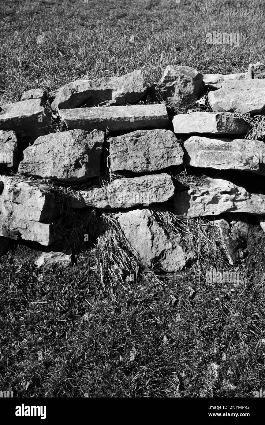 The ruins of an old stone wall on a country hill in a black and white ...