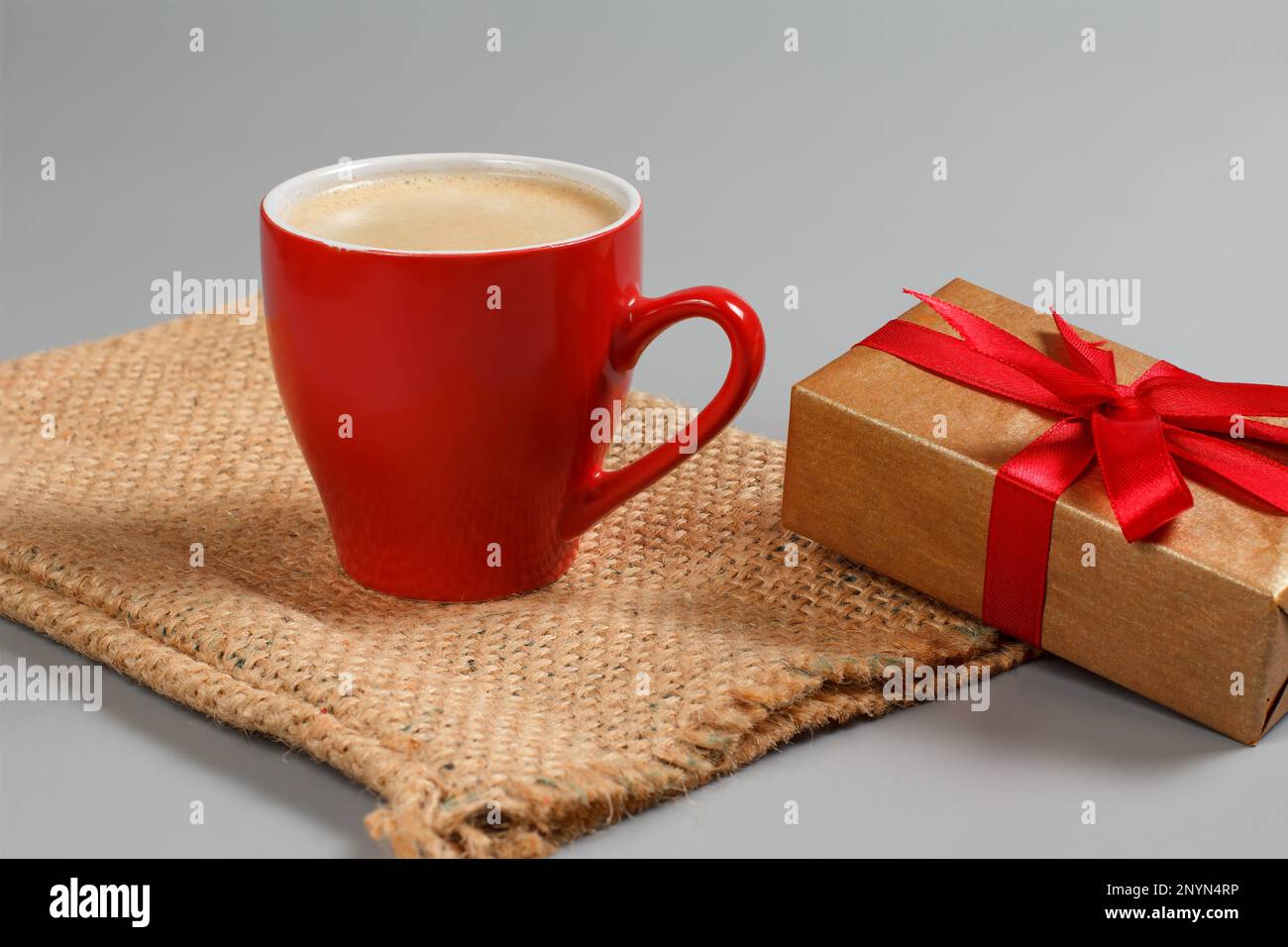 Cup of black coffee and gift box on sackcloth bag. Stock Photo