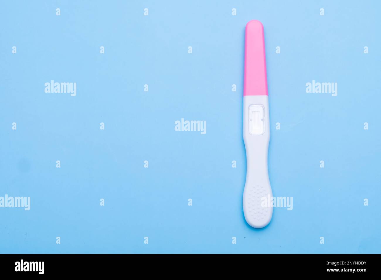 Unused pink and white pregnancy test on the blue background with copy space Stock Photo