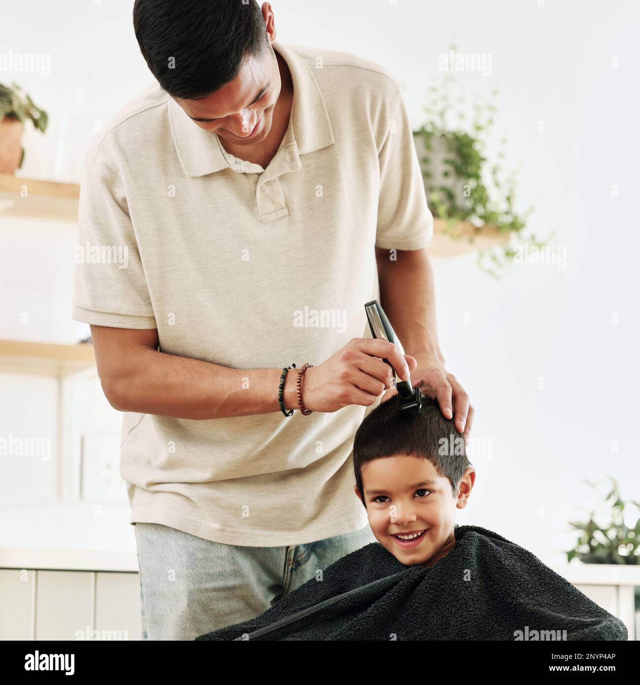 Family, children and haircut with a father shaving the hair of his son together in the home for