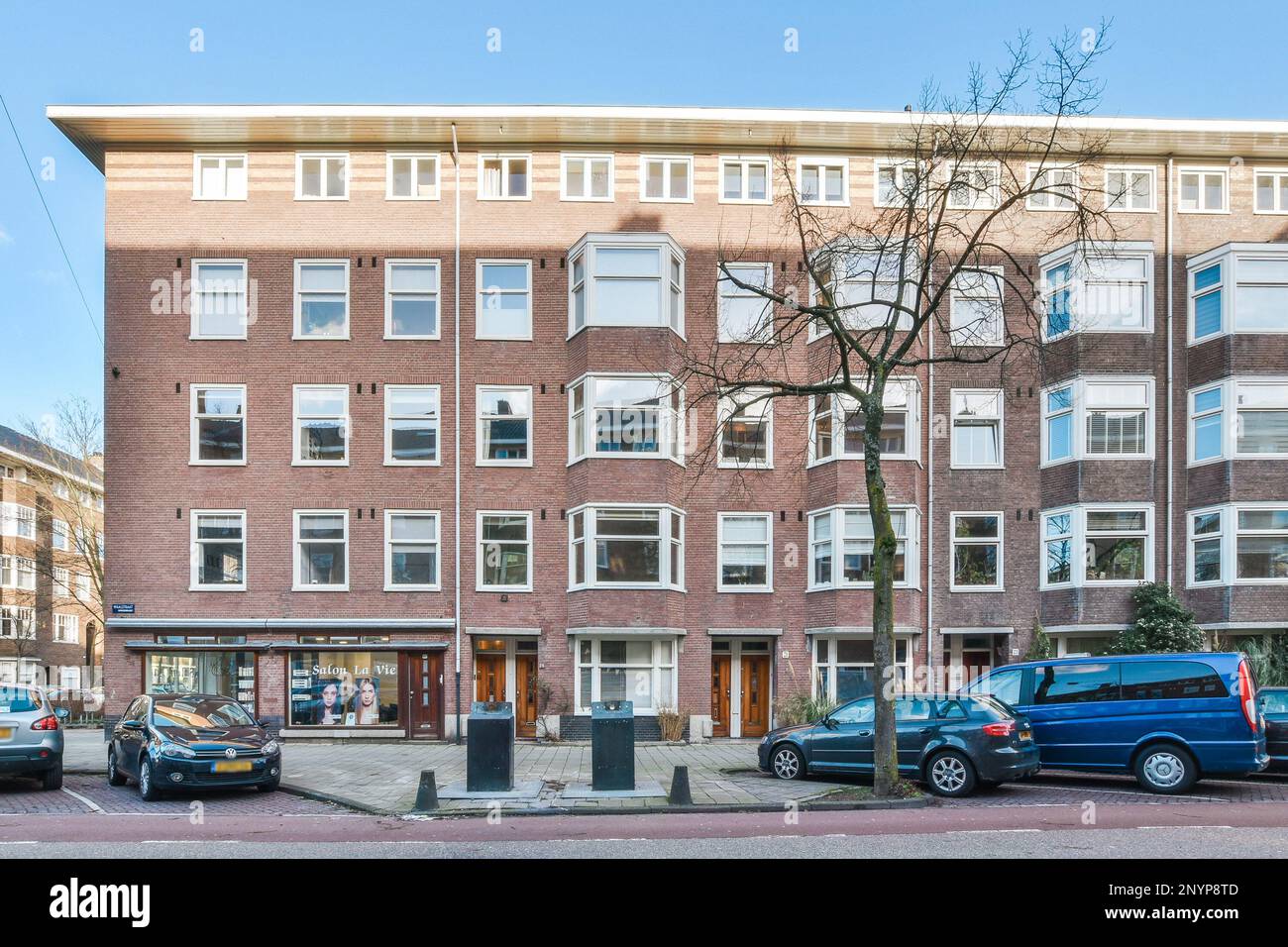 an apartment building with cars parked on the side of the street in ...