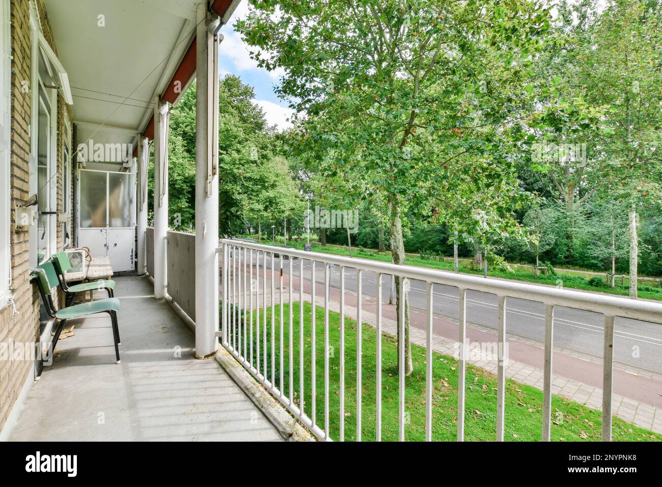 Amsterdam, Netherlands - 10 April, 2021: a porch with chairs and trees on the side walk way, looking out onto the street in front of the house Stock Photo