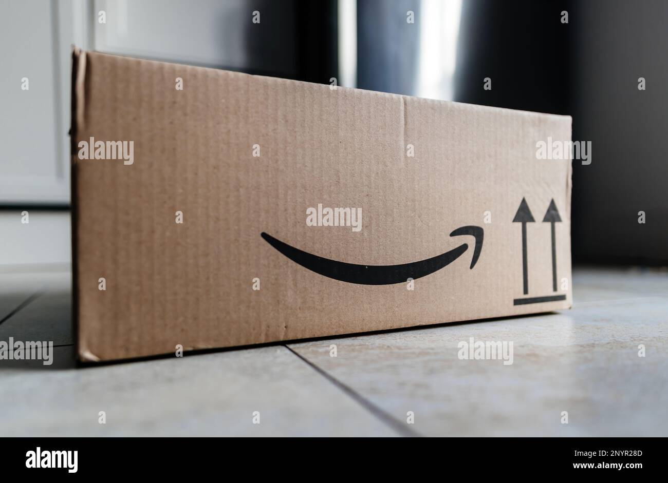 Paris, France - Mar 1, 2023: Amazon Prime cardboard parcel on the floor in the kitchen right before the unboxing unpacking Stock Photo