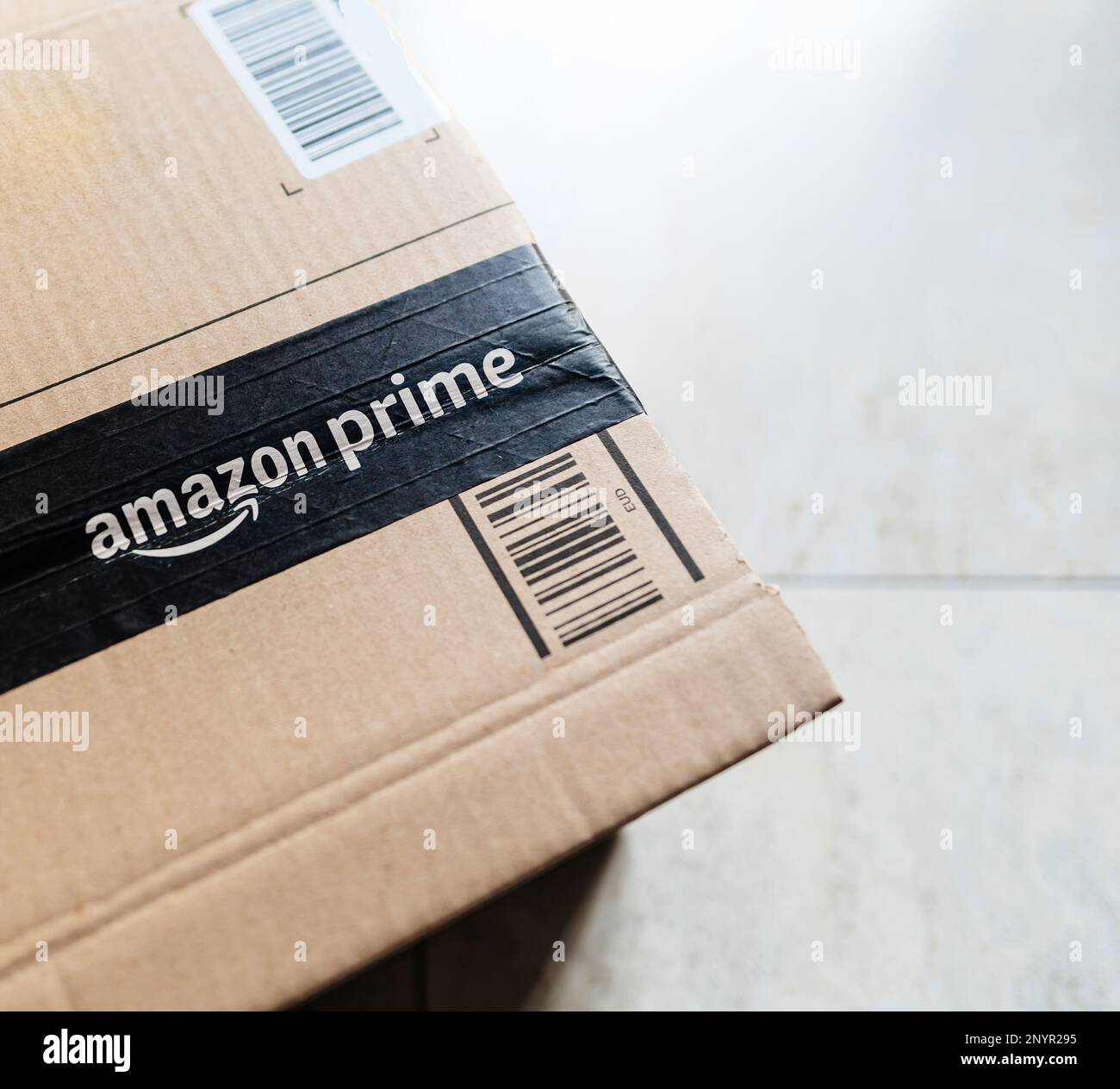 Paris, France - Mar 1, 2023: Detail of Amazon Prime cardboard parcel on the floor right before the unboxing unpacking Stock Photo
