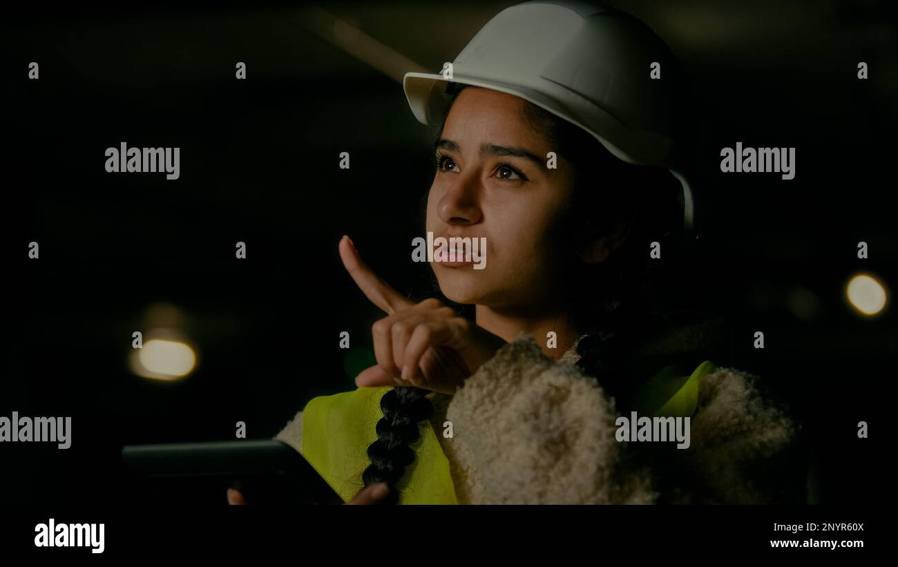 Young arabian woman technician inspector engineer developer wears protecting helmet uniform use electronic digital tablet checking manufacture work Stock Photo