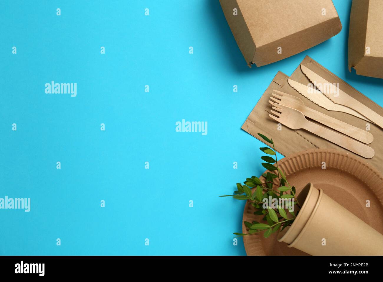 Flat lay of paper and wooden tableware with green twigs on turquoise ...