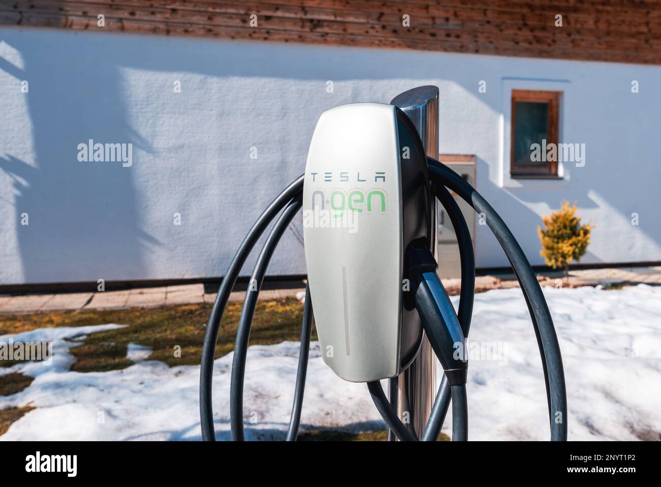 Stara Fuzina, Slovenia - February 21, 2023: Tesla n-gen electric car home charger in house front yard, illustrative editorial Stock Photo