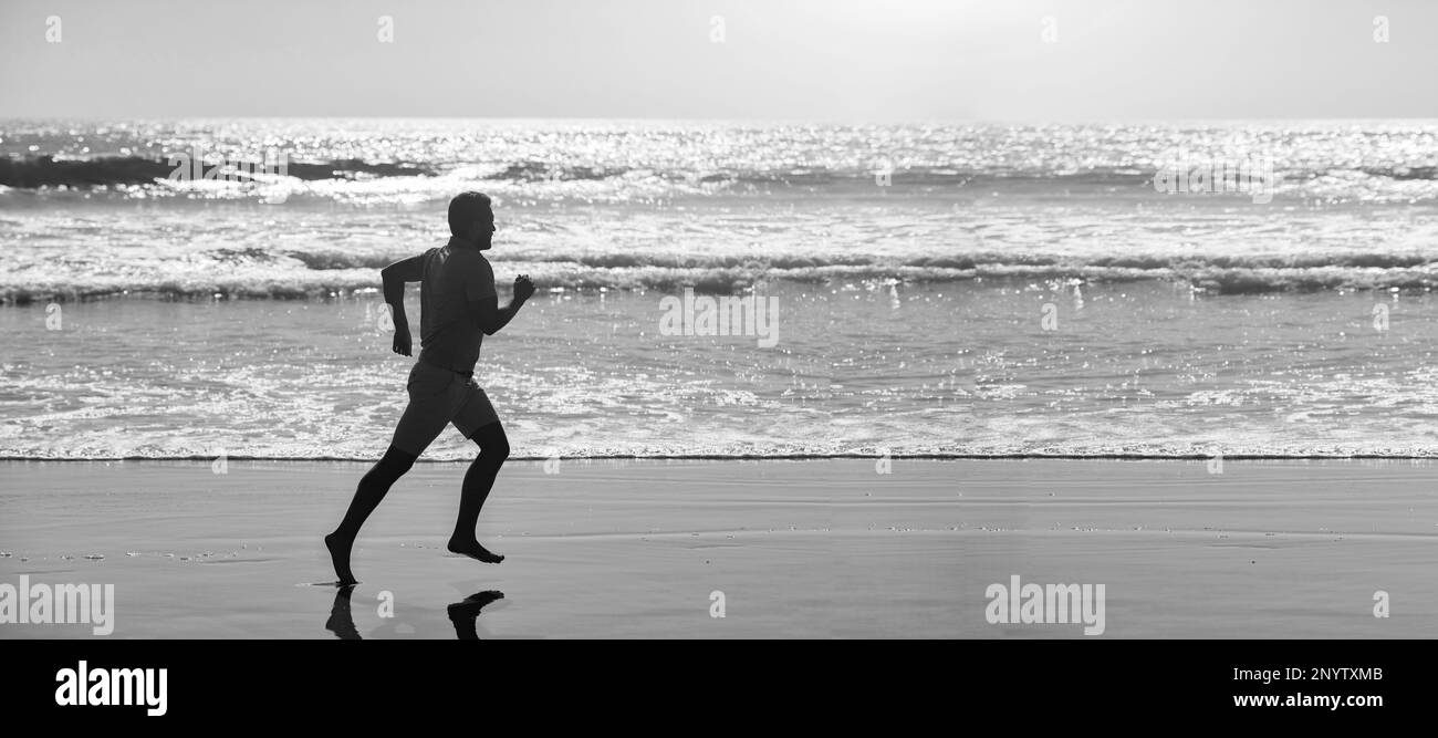 silhouette of sporty man runner sprinting on beach outdoor, achievement. Man running and jumping, banner with copy space Stock Photo